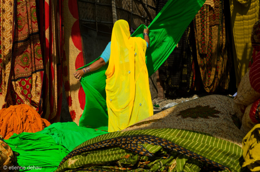 femme déplacant des tissus après les phases de teinture et de séchage, dans une usine indienne de sari.